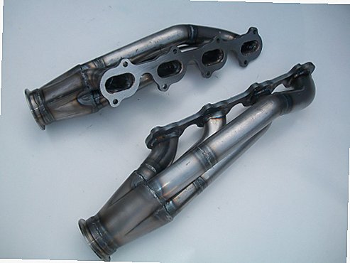 5.4 4V Racing Headers — facing-forward tubular turbo headers in mild steel with V-band flanges and CNC head flanges
